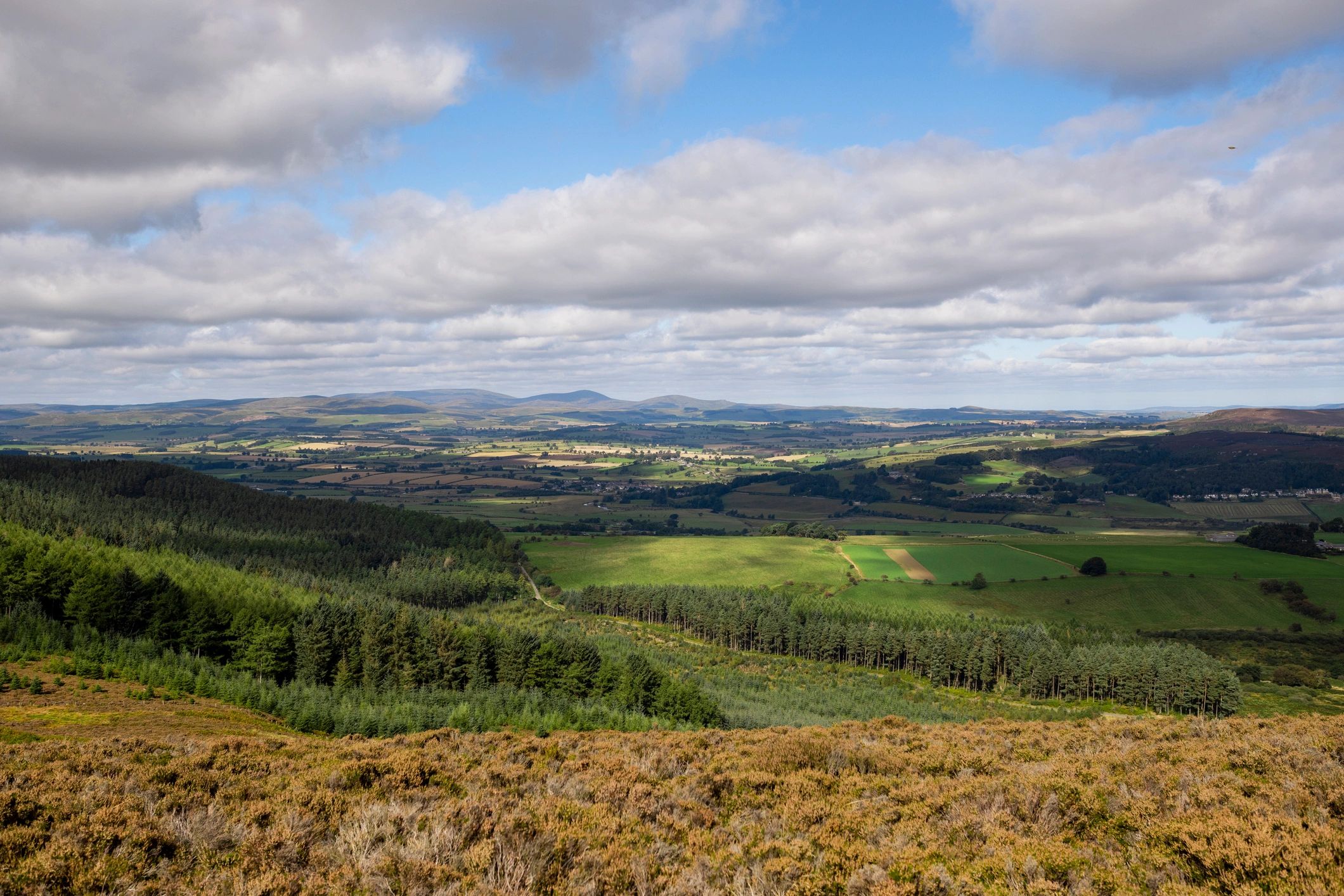 Rolling countryside landscape in Northumberland with sunlight and clouds